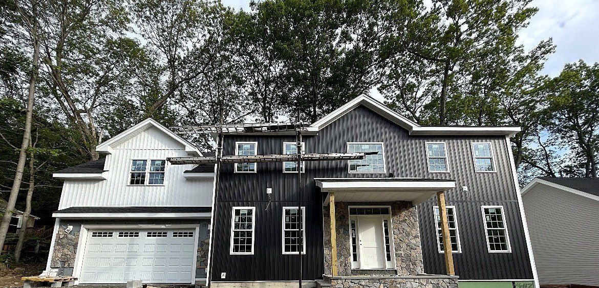 Neighboring home with black vertical siding and a white board-and-batten garage wing