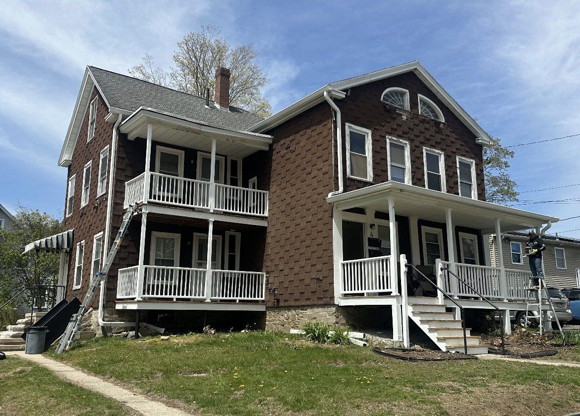 Two-family home before, with weathered brown shake siding