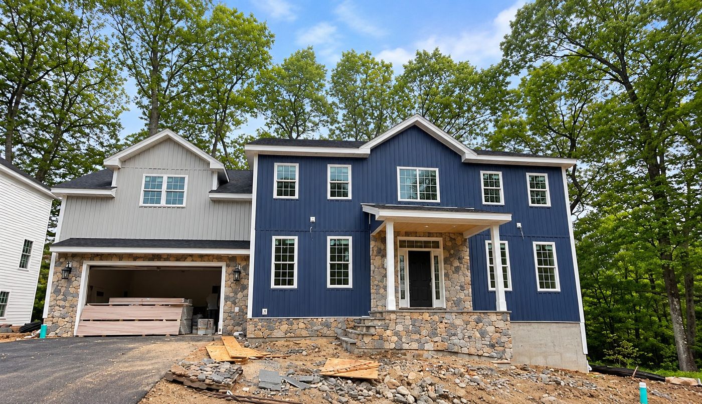 New home with navy vertical siding, a light gray garage wing and stone accents