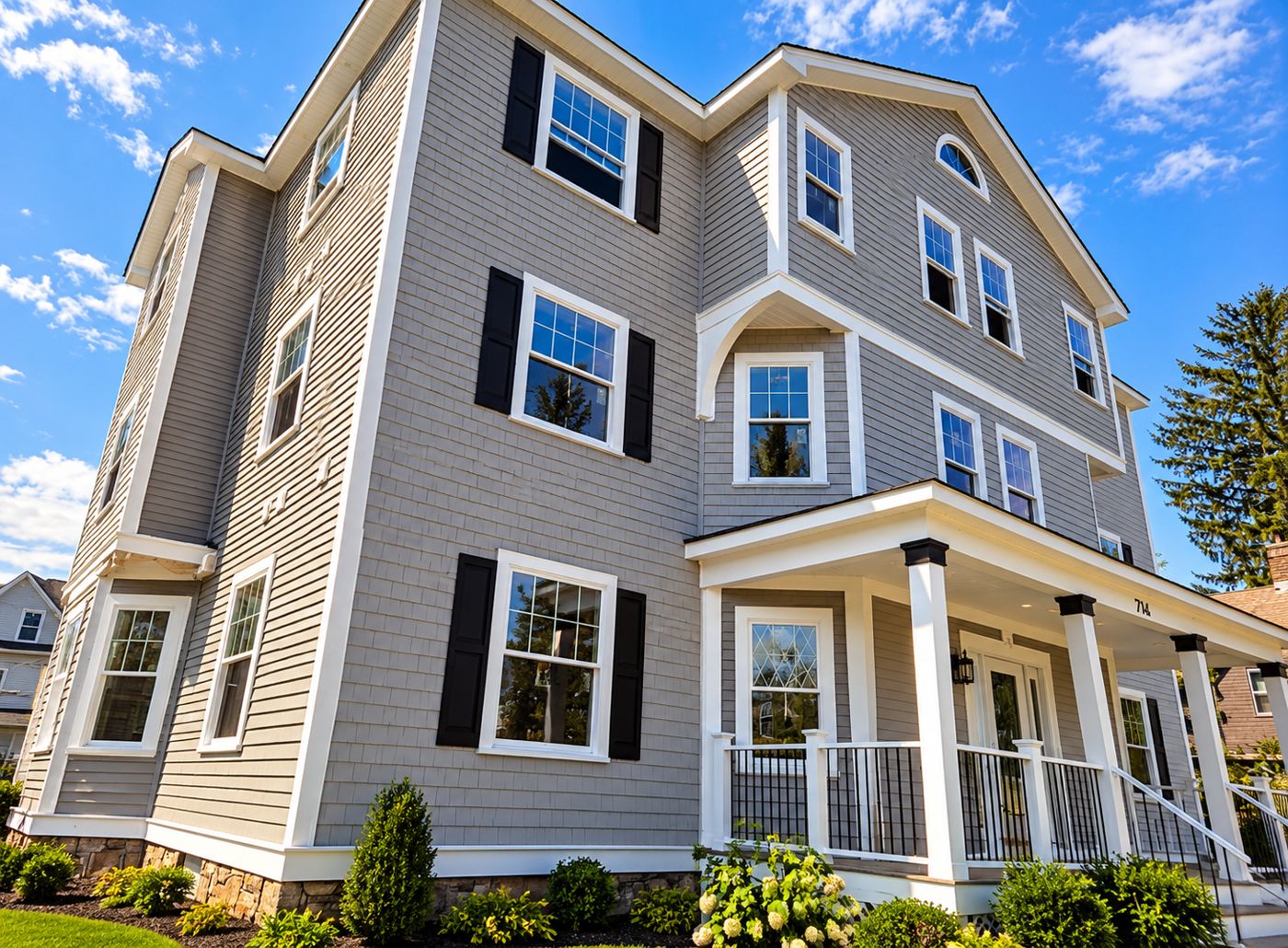 Three-story home with gray shake siding on the main walls and white trim