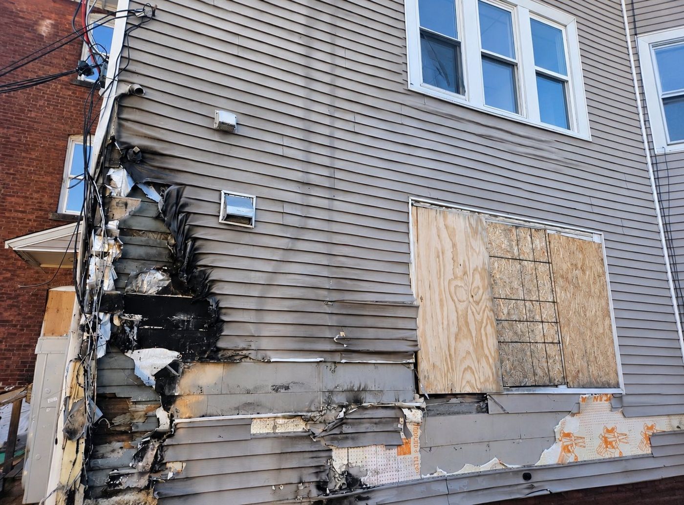 Fire-damaged wall with melted, burned vinyl siding