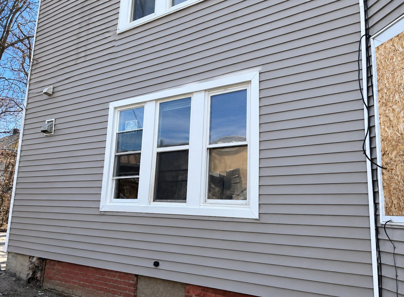 The same wall after repair with new gray siding